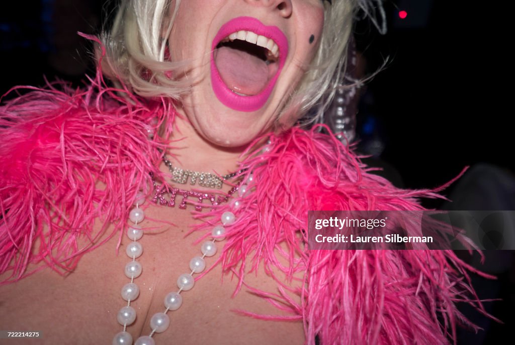 Mid adult woman in party clothes, with pink feather boa and pink lipstick, mid section