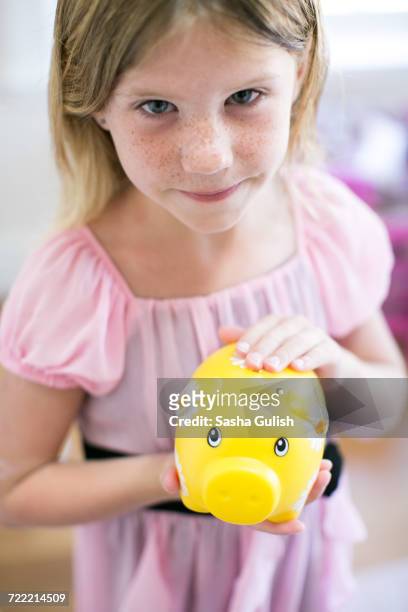 portrait of girl holding piggy bank - blonde girl piggy bank stock-fotos und bilder