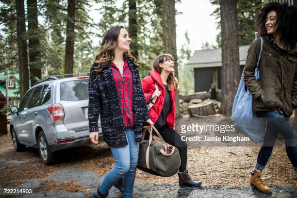 three friends walking away from car, carrying weekend bags - day california arrivals stockfoto's en -beelden