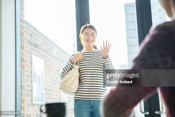 young woman waving hand at coffee shop - japanese greeting stock pictures, royalty-free photos & images