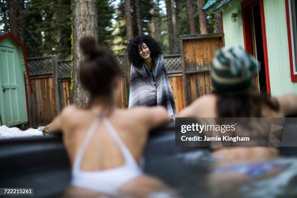 two friends in hot tub, friend standing in front of them wrapped in towel - girls in hot tub fotografías e imágenes de stock