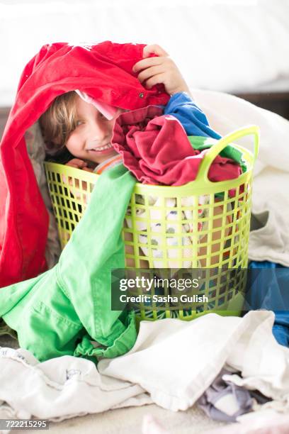 boy sitting in basket amongst laundry - laundry basket imagens e fotografias de stock