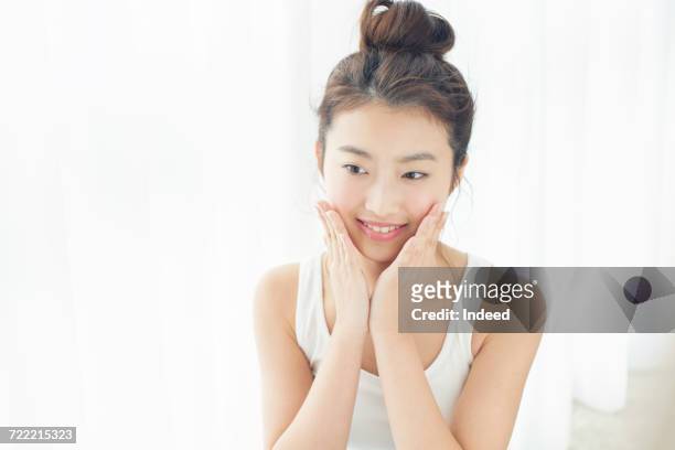 young woman touching her face skin, smiling - 若い女性 日本人 顔 ストックフォトと画像