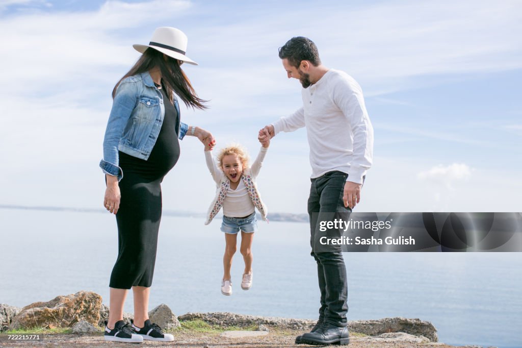 Pregnant mature couple swinging daughter at coast