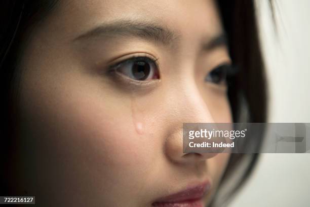 tear is on young womans face - tear face photos et images de collection
