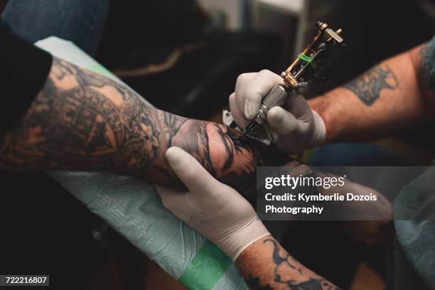 tattooist tattooing young mans arm, close-up - tatuaje fotografías e imágenes de stock