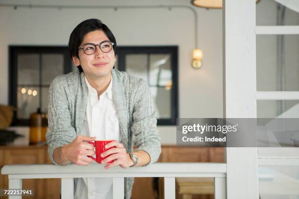 young man drinking coffee in room - 息抜き ストックフォトと画像