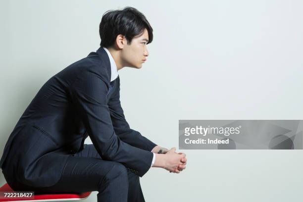 side view of young businessman sitting on chair - business man profile fotografías e imágenes de stock