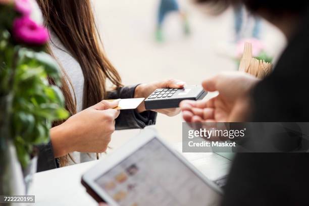 midsection of female customer paying through card reader while owner holding digital tablet in food truck - food truck payments stock pictures, royalty-free photos & images