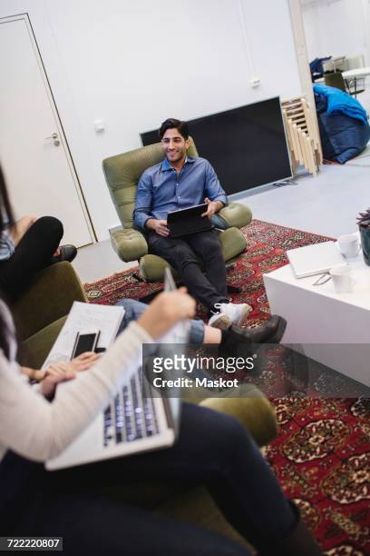 smiling young man discussing with colleagues in creative office - carpet icon stock pictures, royalty-free photos & images