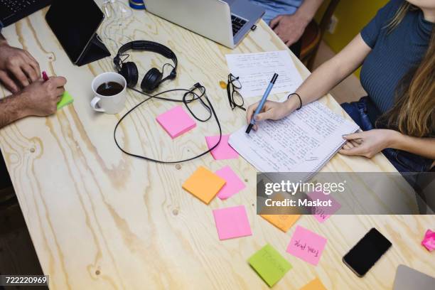 high angle view of young woman writing in book at wooden desk in office - arab businesswoman with books stock-fotos und bilder