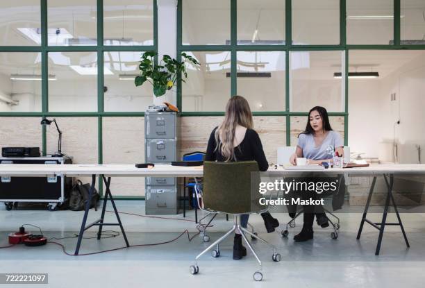 two women working at desk in creative office - office chair back fotografías e imágenes de stock