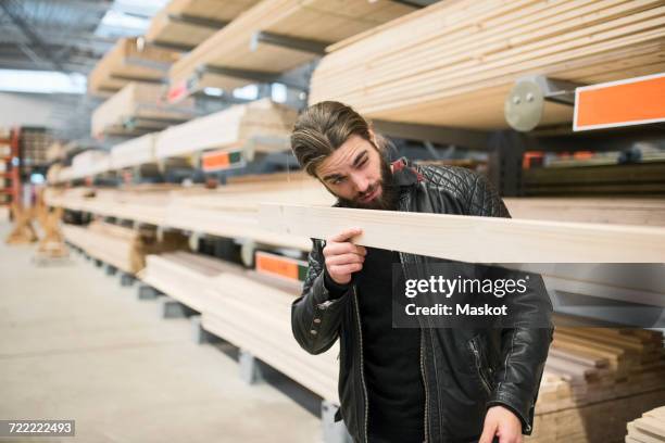 male customer examining wooden plank in hardware store - ferramenta foto e immagini stock