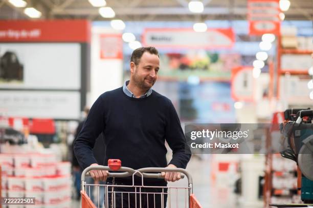 male customer pushing shopping cart at hardware store - men shopping stock pictures, royalty-free photos & images