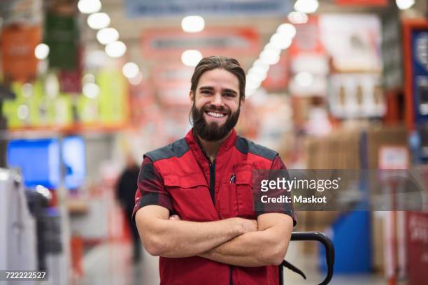 portrait of happy salesman standing arms crossed at hardware store - salesman imagens e fotografias de stock