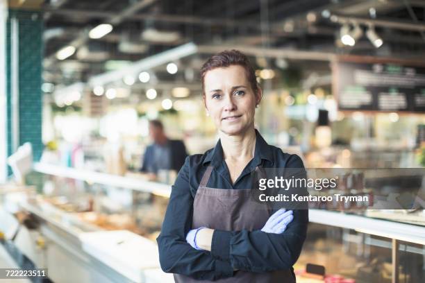 portrait of confident female owner standing arms crossed in supermarket - verkäuferin stock-fotos und bilder