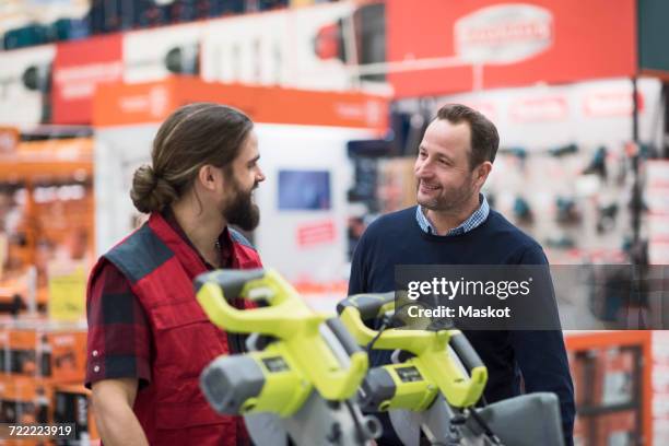 salesman discussing with male customer in hardware store - hardware store fotografías e imágenes de stock