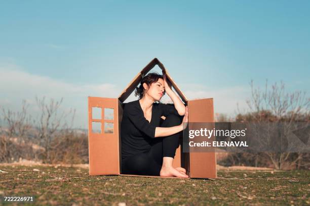 woman sitting in cardboard box house - passt nicht stock-fotos und bilder