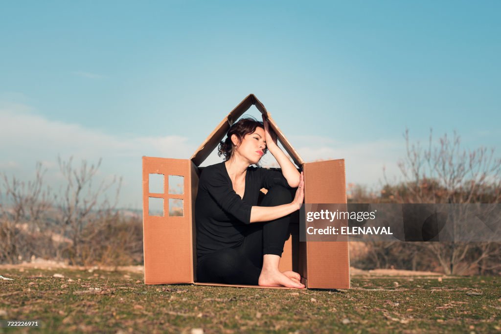 Woman sitting in cardboard box house