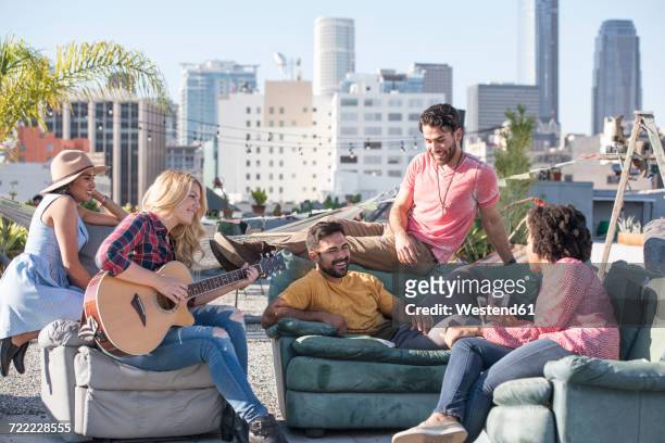 friends having a rooftop party and playing guitar - los angeles garden party stock pictures, royalty-free photos & images