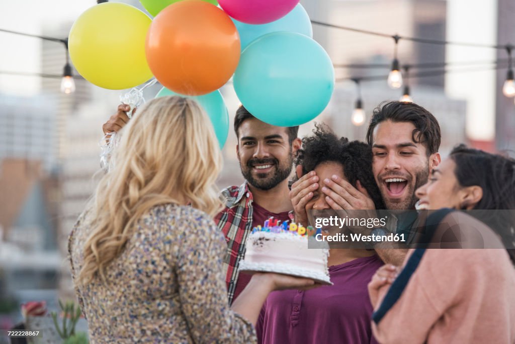 Friends celebrating birthday party on rooftop with birthday cake