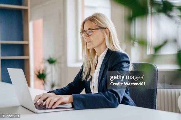 businesswoman using laptop in office - blonde glasses foto e immagini stock