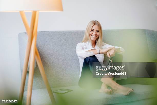portrait of smiling relaxed businesswoman sitting on couch - selective focus stock-fotos und bilder