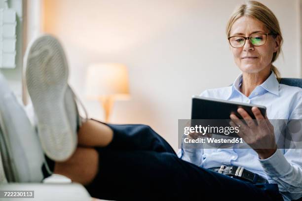 businesswoman sitting down using tablet - woman with tablet stock-fotos und bilder