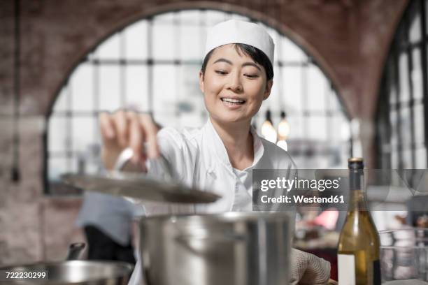 smiling female chef cooking in kitchen - chinese restaurant photos et images de collection