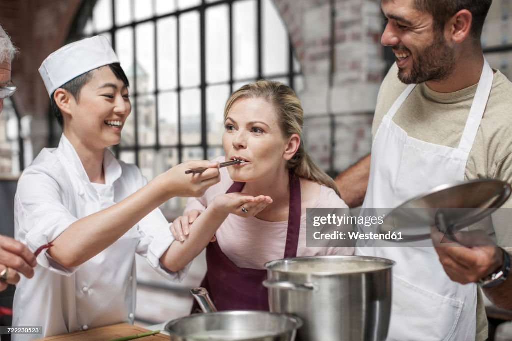 Female student tasting from pot in cooking class