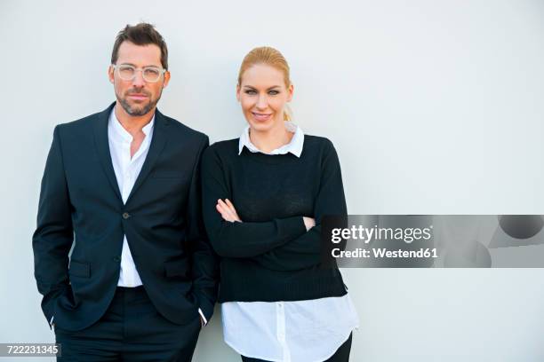 portrait of confident businessman and woman against white wall - adults standing side by side stock pictures, royalty-free photos & images