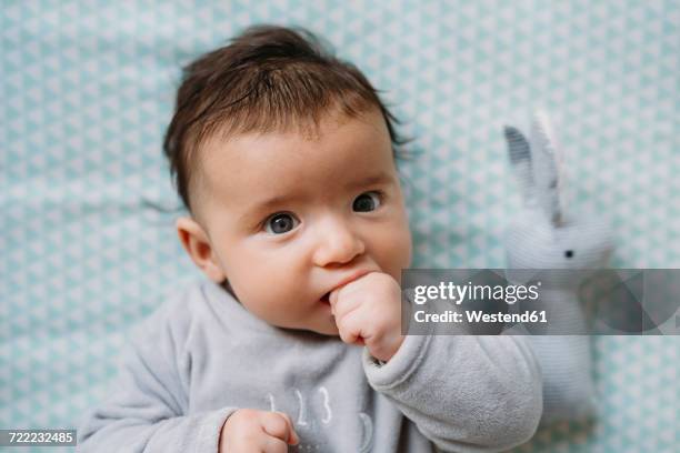 portrait of baby girl lying on bed sucking thumb - finger in mouth stock pictures, royalty-free photos & images