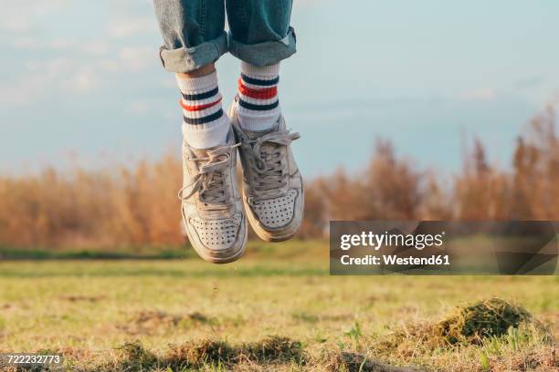 shoes of man jumping on meadow - white shoes stockfoto's en -beelden