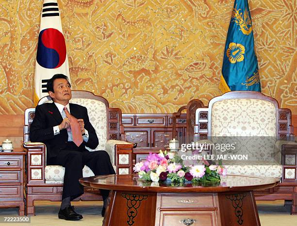 Japanese Foreign Minister Taro Aso adjusts his tie before meeting with South Korean President Roh Moo-hyun at the presidential Blue House in Seoul 20...