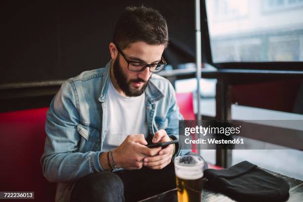 young man text messaging in a pub - young men drinking beer stock pictures, royalty-free photos & images