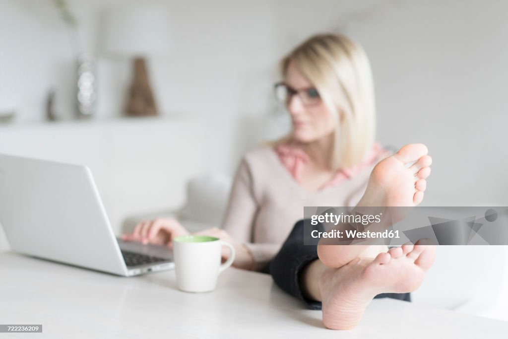 Woman sitting at table with feet up using laptop