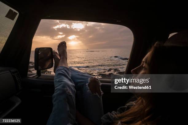 woman sitting in car at sunset - forte contrasto foto e immagini stock