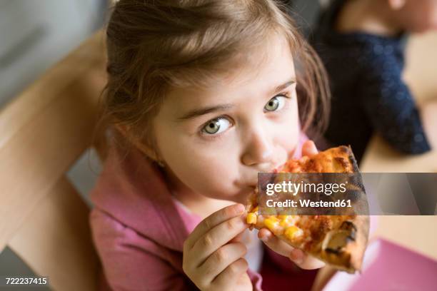 little girl at home eating slice of pizza - pizza slice stock pictures, royalty-free photos & images