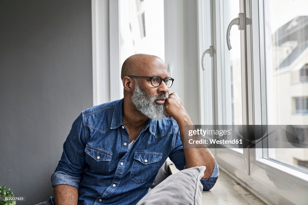 Mature man sitting at window, looking worried