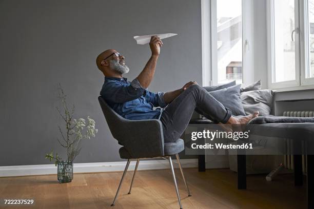mature man plying with paper plane - paper airplane stock-fotos und bilder