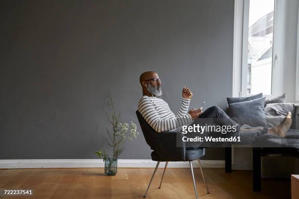 mature man sitting with feet up, using smartphone - feet up stock pictures, royalty-free photos & images