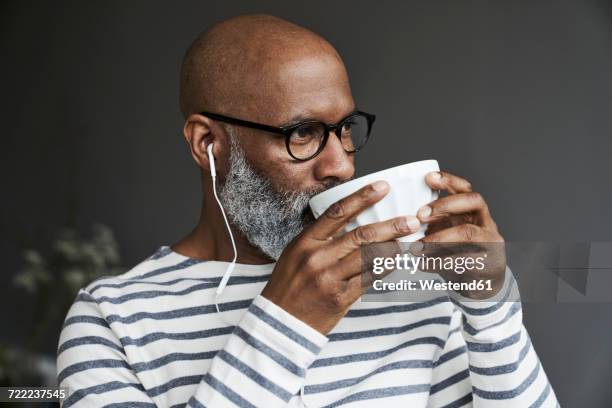 mature man with earphones drinking coffee - coffee indulgence stock pictures, royalty-free photos & images