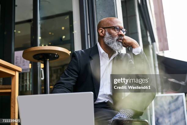 mature businessman sitting in cafe using laptop - city break stock-fotos und bilder