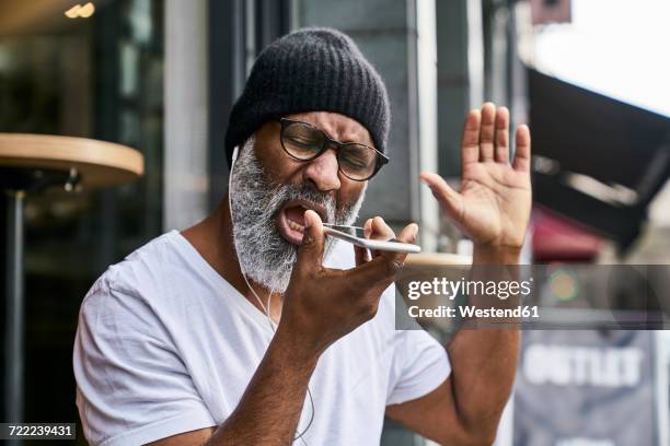 mature businessman talking on the phone, wearing earphones - angry on phone photos et images de collection