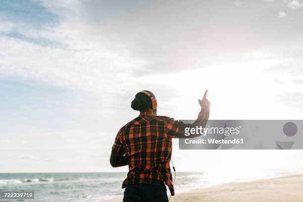 back view of man walking on the beach listening music with headphones - index finger stock pictures, royalty-free photos & images