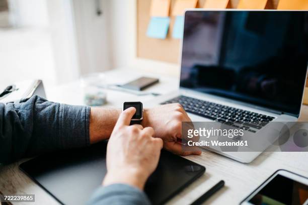 man using smartwatch at desk - autonomo smartphone tablet fotografías e imágenes de stock
