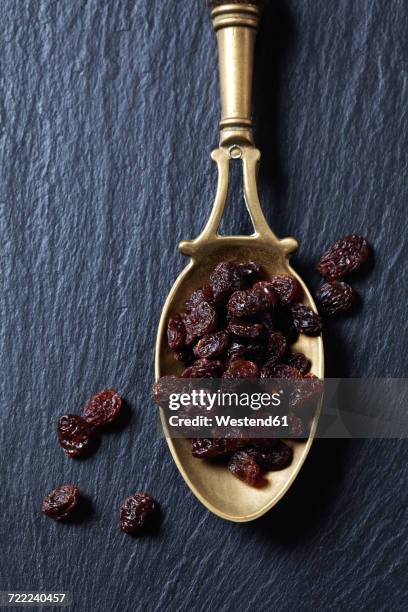 raisins on brass spoon and slate - raisin stock pictures, royalty-free photos & images