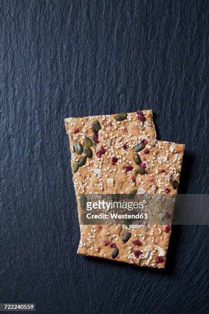 two slices of crispbread with cranberries, coconut and pumpkin seed on slate - crispbread stock pictures, royalty-free photos & images
