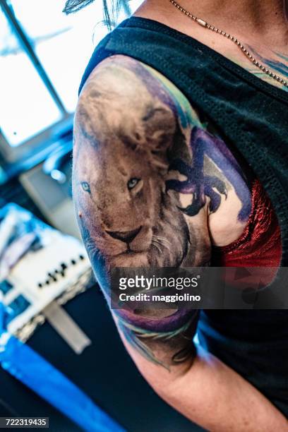 midsection of woman with lion tattoo on shoulder at studio - lion tattoo stock-fotos und bilder