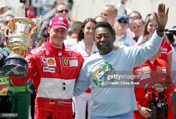 Michael Schumacher of Germany and Ferrari receives a trophy for his achievements in Formula One Grand Prix racing from Brazilian soccer legend Pele...